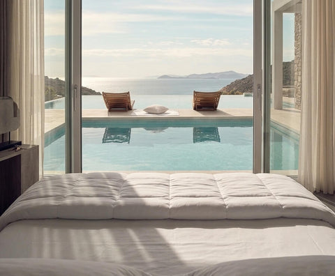 Elegantes Hotelzimmer mit Blick auf Pool und Meer, ausgestattet mit hochwertigen Bettwaren im exklusiven Luxushotel-Ambiente.