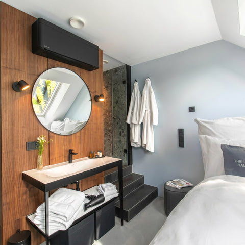 Stilvoll eingerichtetes Luxushotelzimmer mit hochwertigem Bett, offenem Waschbereich, rundem Spiegel, warmen Holzelementen und sorgfältig arrangierten Hoteltextilien für ein exklusives Übernachtungserlebnis.