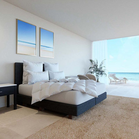 Luxuriöse Gänsedaunendecke auf modernem Bett in hellem Designer-Schlafzimmer mit Meerblick und hochwertigen Kissen
