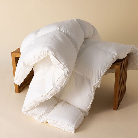 Excellence Natürlicher Topper mit voluminöser Füllung auf einem Holzhocker, präsentiert als hochwertige Ergänzung für mehr Schlafkomfort.