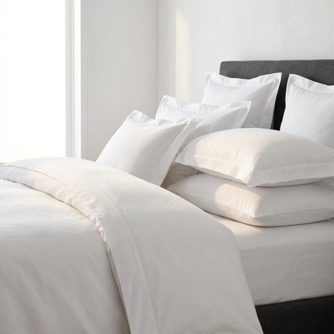 Elegantes Hotelbett mit weißer Bettwäsche, flauschigen Kissen und hochwertiger Ausstattung als Symbol für luxuriösen Schlafkomfort und exklusive Hotelbettwäsche.
