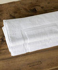 Nahaufnahme einer hochwertigen weißen Badematte aus dem Premium Luxushotel Badematten 3er Set mit sauber verarbeitetem Rand und strapazierfähiger Struktur.