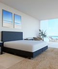 Ein modernes, minimalistisches Boxspringbett mit einem perfekt sitzenden, weißen Premium-Spannbettlaken in einem hellen Schlafzimmer mit großer Fensterfront und Blick auf den Strand.